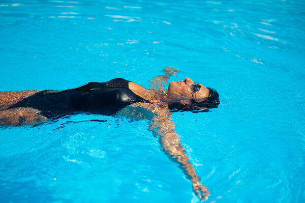 Beautiful black haired woman near pool in swimwear
