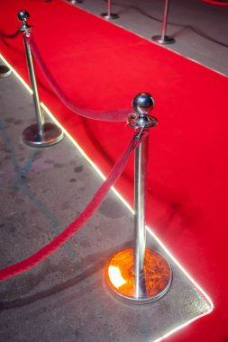 Uzun kırmızı halı ipi engelleri giriş arasında.