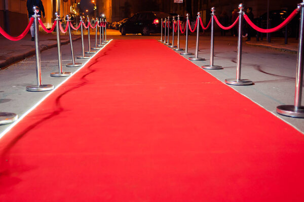 Long red carpet between rope barriers on entrance.
