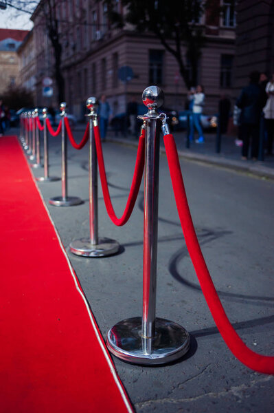 Long red carpet between rope barriers on entrance.