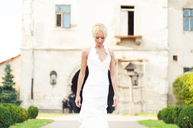 Beyaz elbiseli güzel sarışın kadın sokakta poz veriyor.