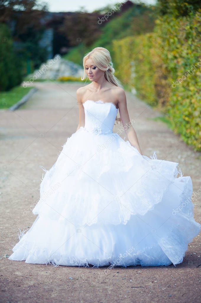 Sensual bride blonde in wedding dress near the palace before the wedding ceremony