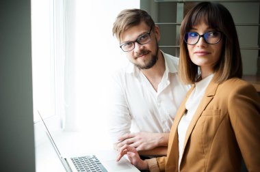 İki genç arkadaşları giyinmiş casual beyaz iç dizüstü bilgisayar kullanarak