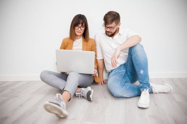 İki genç arkadaşları giyinmiş casual beyaz iç dizüstü bilgisayar kullanarak