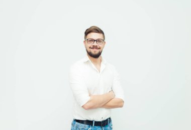 Beyaz gömlek ve gri arka plan üzerinde rahat kıyafetler giymiş gözlüklü genç bir adam portresi