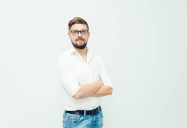 Beyaz gömlek ve gri arka plan üzerinde rahat kıyafetler giymiş gözlüklü genç bir adam portresi