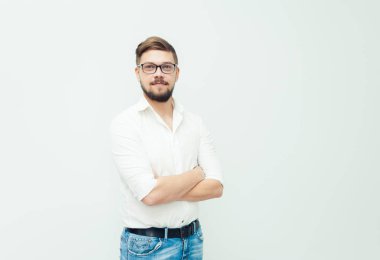 Beyaz gömlek ve gri arka plan üzerinde rahat kıyafetler giymiş gözlüklü genç bir adam portresi