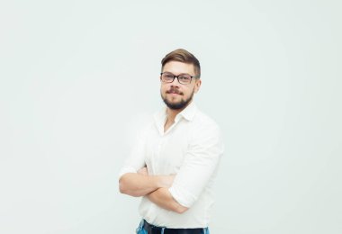 Beyaz gömlek ve gri arka plan üzerinde rahat kıyafetler giymiş gözlüklü genç bir adam portresi