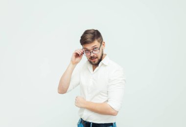 Beyaz gömlek ve gri arka plan üzerinde rahat kıyafetler giymiş gözlüklü genç bir adam portresi