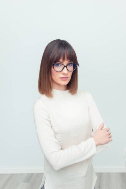 Gözlüklü, güzel genç kadın üzerinde gri bir arka plan olarak rahat, giyinmiş. Ofis çalışanı. Tasarımcısı.