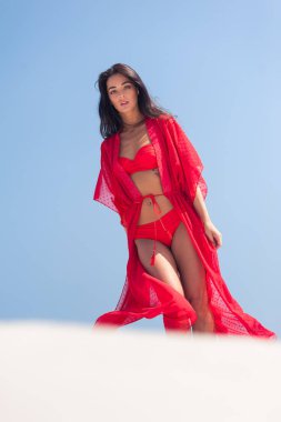 Kumda poz veren güzel bir kadın. Yaz modası kırmızı mayo.