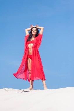Kumda poz veren güzel bir kadın. Yaz modası kırmızı mayo.
