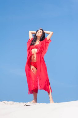 Kumda poz veren güzel bir kadın. Yaz modası kırmızı mayo.