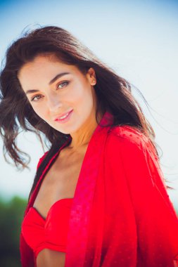 Kumda poz veren güzel bir kadın. Yaz modası kırmızı mayo.