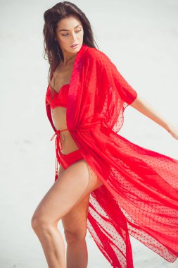 Kumda poz veren güzel bir kadın. Yaz modası kırmızı mayo.