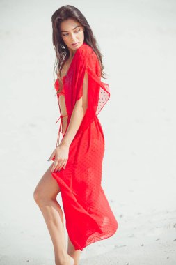 Kumda poz veren güzel bir kadın. Yaz modası kırmızı mayo.