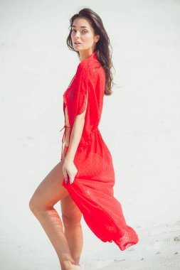 Kumda poz veren güzel bir kadın. Yaz modası kırmızı mayo.