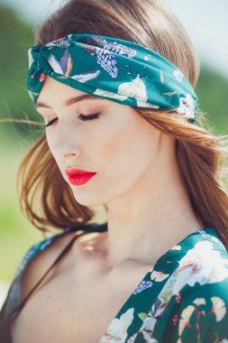 Kumsalda yürüyen güzel genç bir kadın, yeşil çöl kıyafetleri.