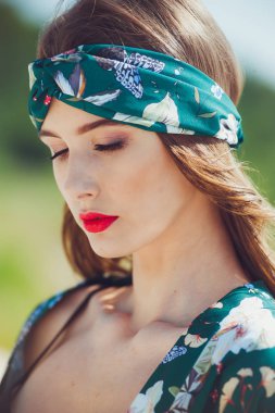 Kumsalda yürüyen güzel genç bir kadın, yeşil çöl kıyafetleri.