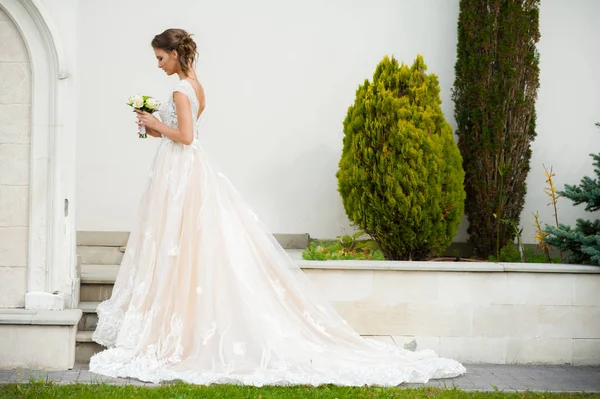 結婚式の花束と長いウェディングドレスの美しい花嫁 — ストック写真