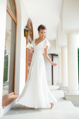 Düğün seremonisinden önce beyaz sarayın yakınında açık renkli, uzun beyaz elbiseli zarif bir kadın yürüyordu..