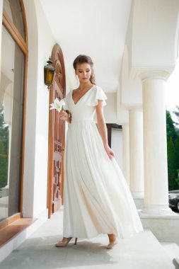 Düğün seremonisinden önce beyaz sarayın yakınında açık renkli, uzun beyaz elbiseli zarif bir kadın yürüyordu..