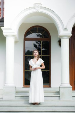 Düğün seremonisinden önce beyaz sarayın yakınında açık renkli, uzun beyaz elbiseli zarif bir kadın yürüyordu..