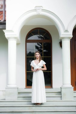 Düğün seremonisinden önce beyaz sarayın yakınında açık renkli, uzun beyaz elbiseli zarif bir kadın yürüyordu..