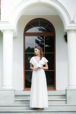 Düğün seremonisinden önce beyaz sarayın yakınında açık renkli, uzun beyaz elbiseli zarif bir kadın yürüyordu..