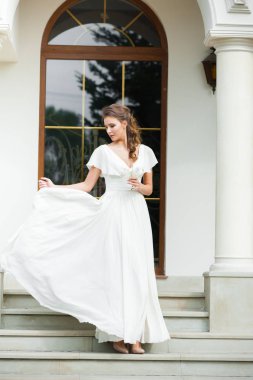 Düğün seremonisinden önce beyaz sarayın yakınında açık renkli, uzun beyaz elbiseli zarif bir kadın yürüyordu..