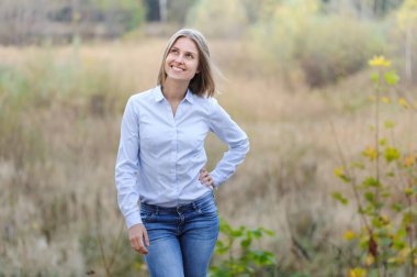 Sıradan giyinmiş, kuru bir alanda gülümseyen bir iş kadını.