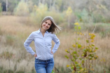 Sıradan giyinmiş, kuru bir alanda gülümseyen bir iş kadını.