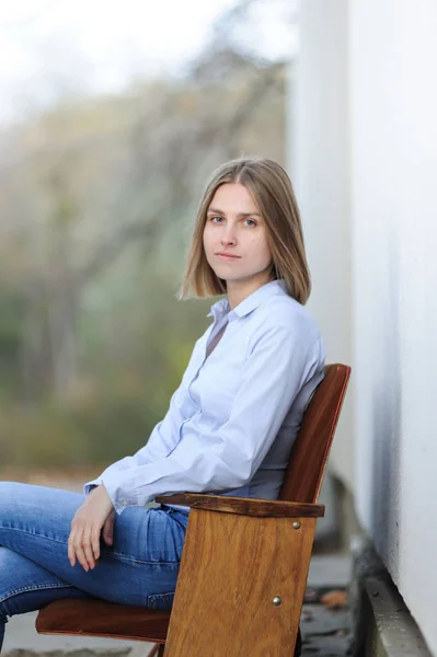 Portrait of a young smiling woman wearing casual sitting on a chair outdoor
