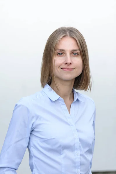 Portrait of a young successful woman working IT company on the background of the white wall