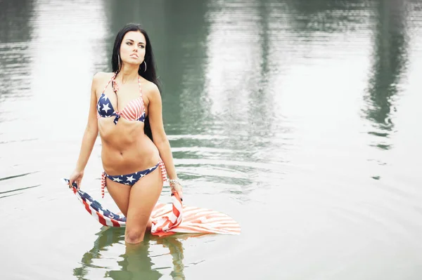 美丽健康的年轻女子穿着泳衣 海滩上挂着美国国旗 — 图库照片