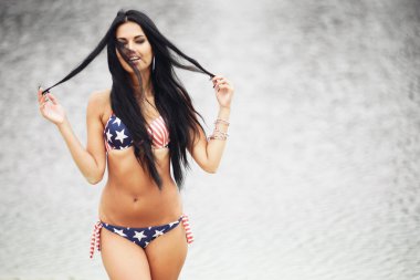 Amerika 'nın Bağımsızlık Günü' nü kutlayan neşeli kadın kumsalda Amerikan bayrağıyla