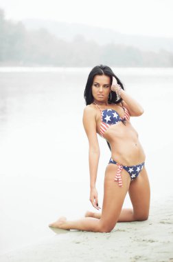 Amerika 'nın Bağımsızlık Günü' nü kutlayan neşeli kadın kumsalda Amerikan bayrağıyla