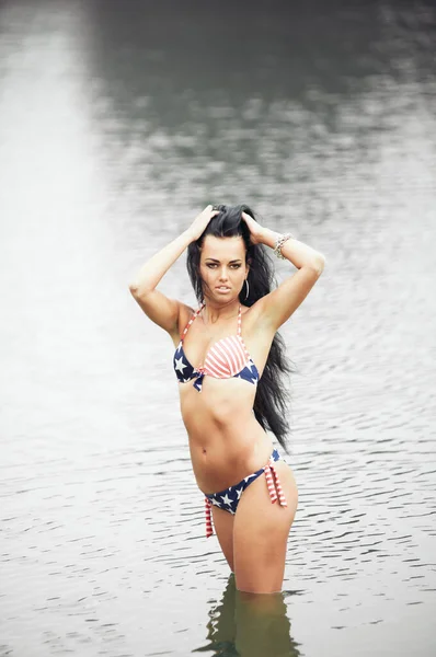 ビーチでアメリカ国旗と水着の美しいフィットネス若い女性 — ストック写真