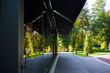 Geniş panoramik pencereleri ve peyzajı olan modern bir binanın ön cephesi.