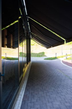 Geniş panoramik pencereleri ve peyzajı olan modern bir binanın ön cephesi.