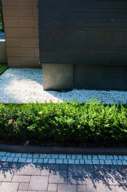 Geniş panoramik pencereleri ve peyzajı olan modern bir binanın ön cephesi.