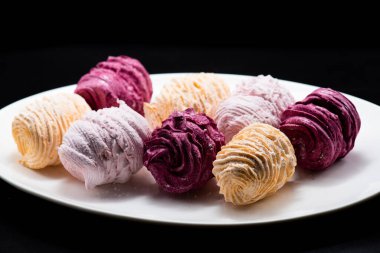 Koyu bir arka planda tabakta leziz marşmelovlar.