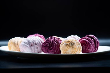 Koyu bir arka planda tabakta leziz marşmelovlar.