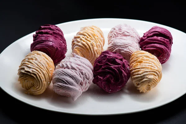 Koyu bir arka planda tabakta leziz marşmelovlar.