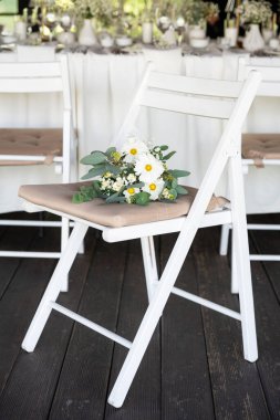 wedding chairs decorated with white flowers.
