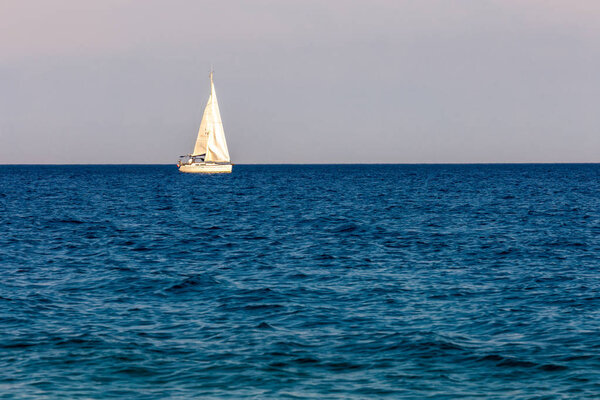 The sailing boat in the blue summer sea