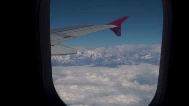 Wolken en Himalaya onder de vleugels van een vliegtuig — Stockvideo