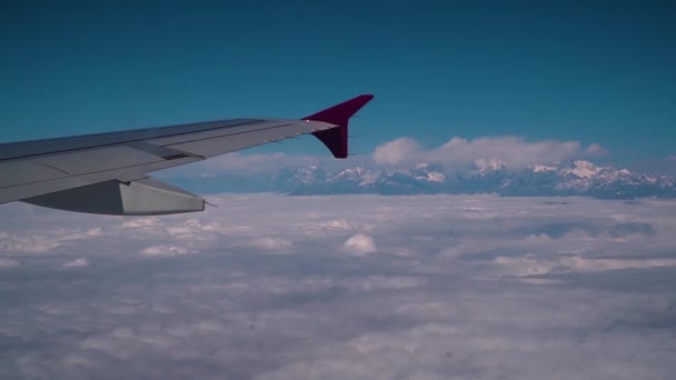Wolken en Himalaya onder de vleugels van een vliegtuig — Stockvideo