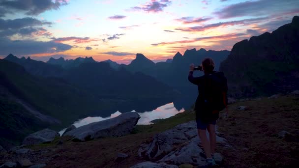 Νεαρή γυναίκα ταξιδιώτης σε ένα φόντο των βουνών παίρνει φωτογραφίες σε ένα κινητό τηλέφωνο — Αρχείο Βίντεο