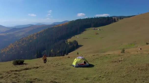 Aéreo - Voando em torno de um turista com uma mochila e uma tenda na encosta da montanha — Vídeo de Stock